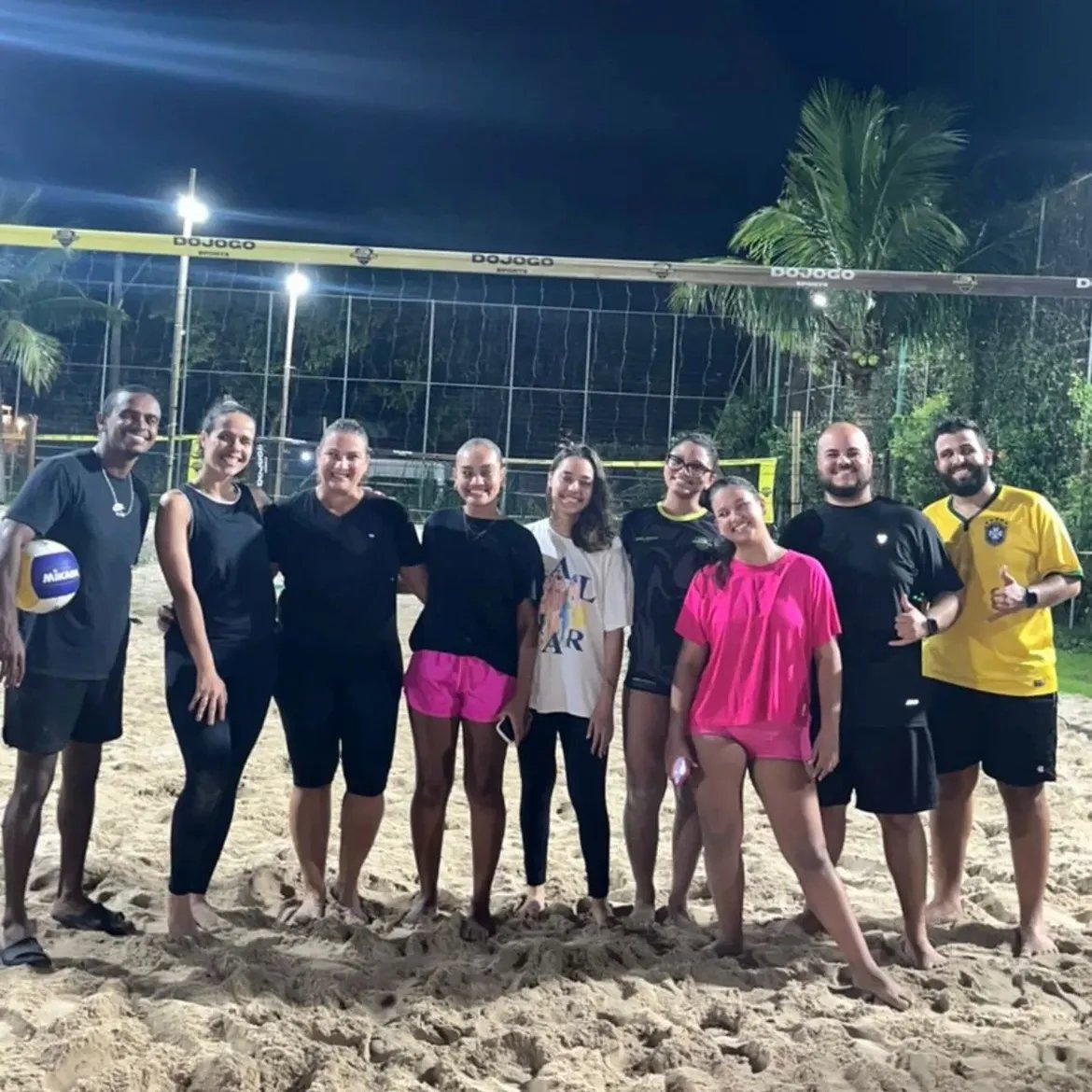 Turma de vôlei de praia da Arena BS reunida na quadra iluminada à noite