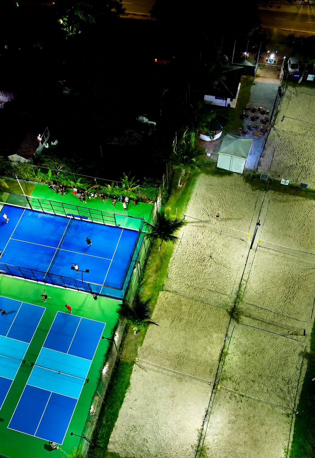 Vista aérea noturna da Arena BS Beach Sports em Búzios com quadras iluminadas